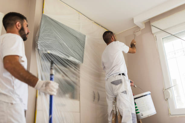men in uniforms finishing renovation, painting the walls white at an apartment